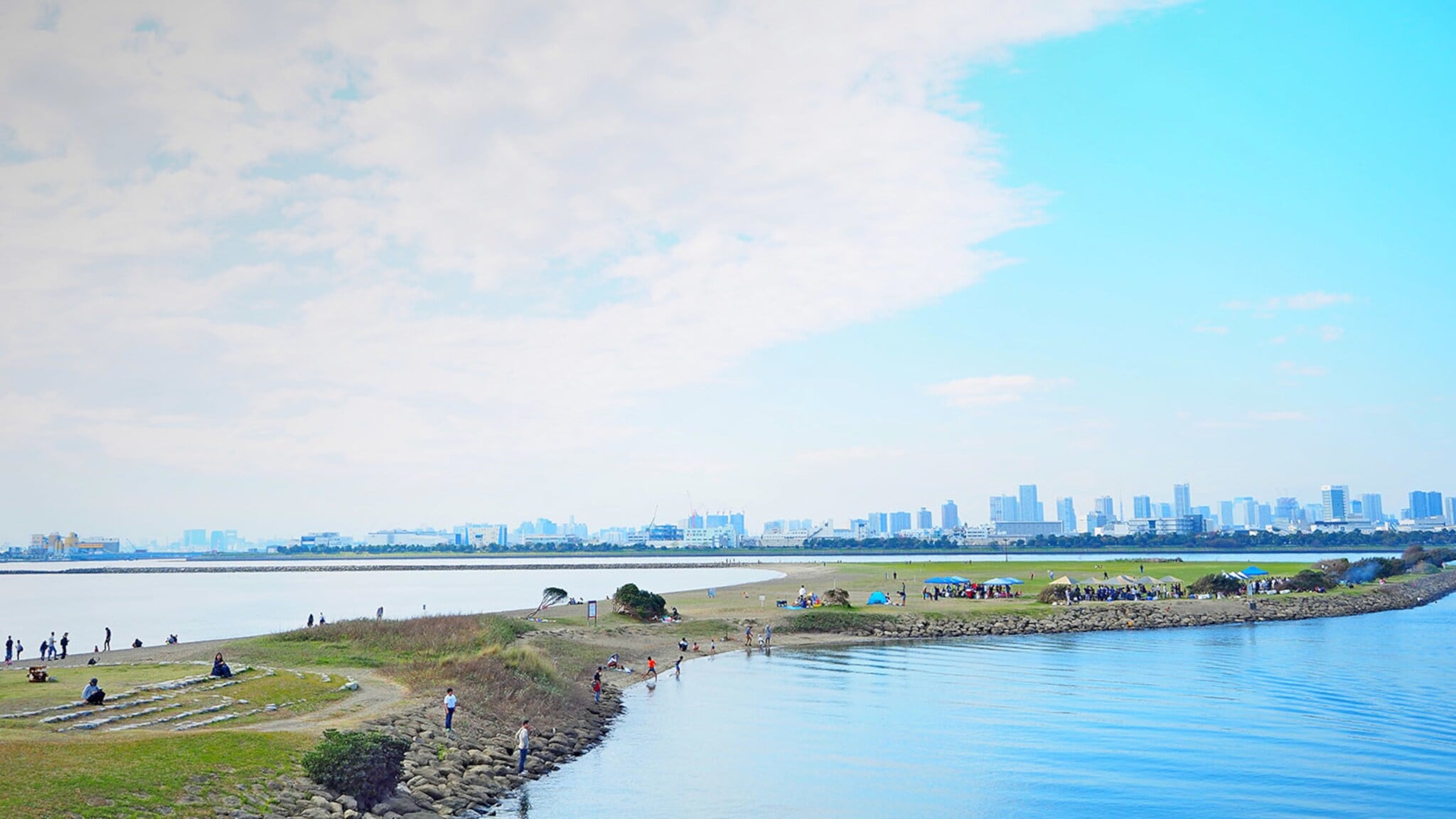 Personen auf einer künstlich angelegten Landzunge im Wasser vor der Skyline von Tokio. Personen auf einer künstlich angelegten Landzunge im Wasser vor der Skyline von Tokio.