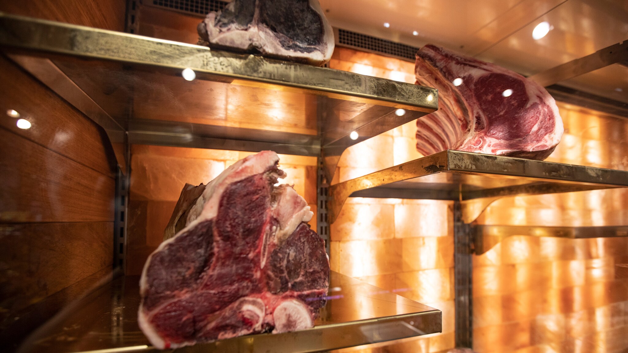 Dicke Fleischstücke mit Knochen lagern in einem klimatisierten Reifeschrank