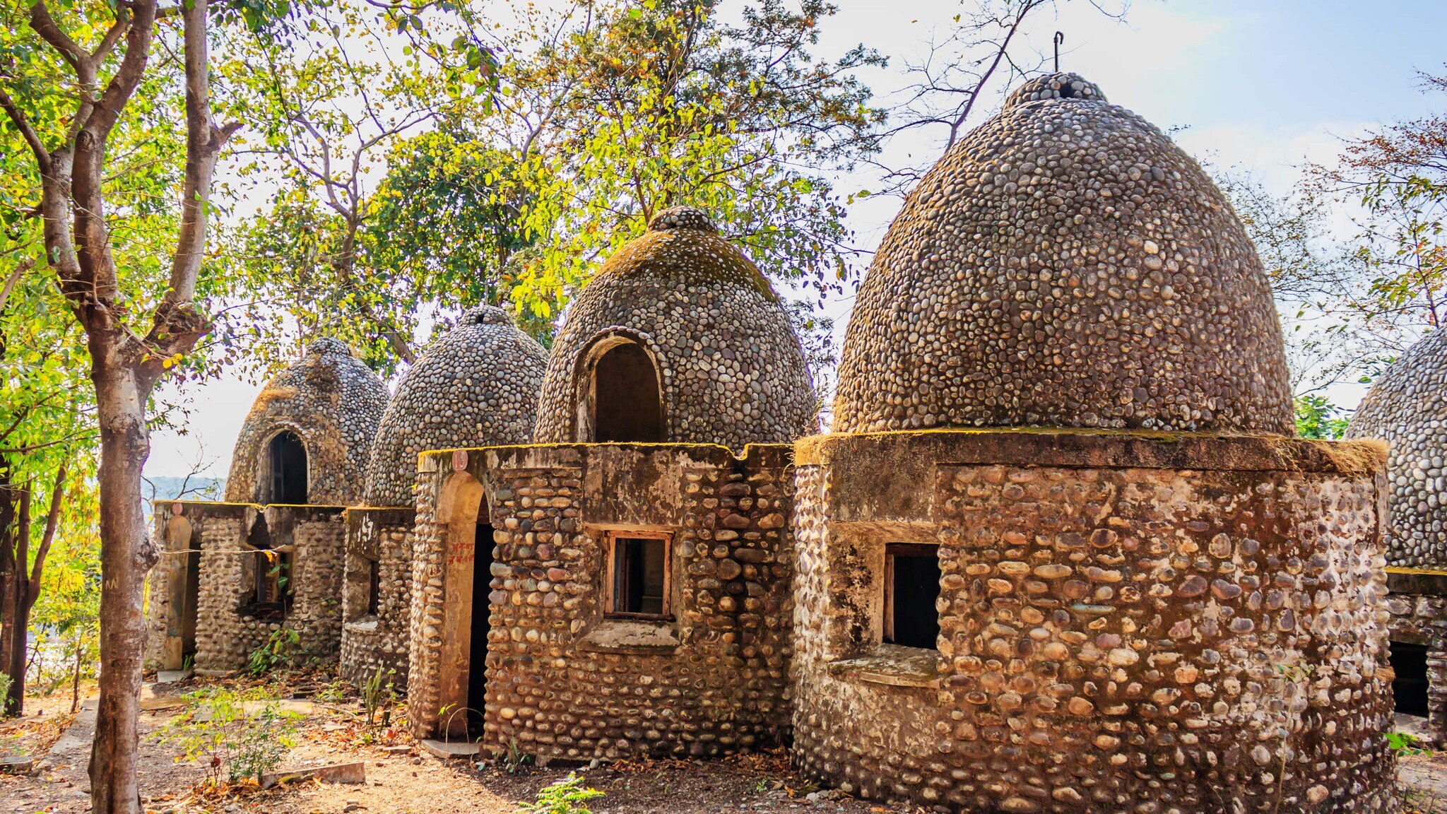 Vier kuppelförmige Gebäude aus kleinen Steinen in einem bewaldeten Gebiet Vier kuppelförmige Gebäude aus kleinen Steinen in einem bewaldeten Gebiet