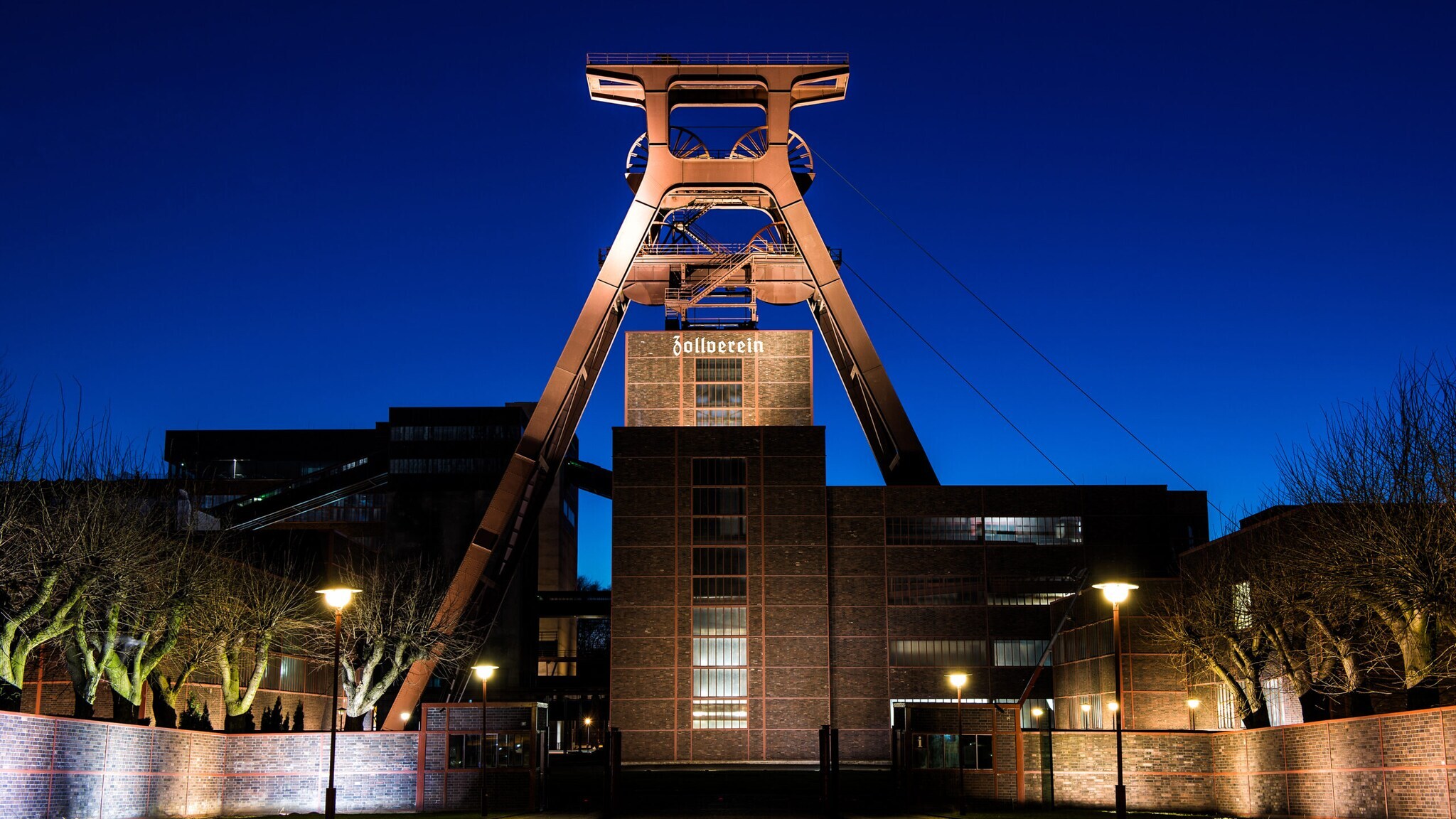 Fördergerüst der Zeche Zollverein mit beleuchtetem Zollverein-Schriftzug bei Abenddämmerung. Fördergerüst der Zeche Zollverein mit beleuchtetem Zollverein-Schriftzug bei Abenddämmerung.