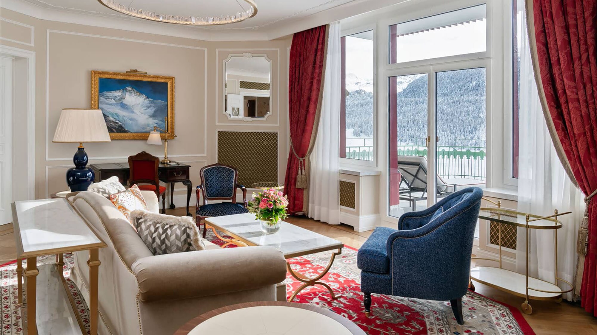 Edle, helle Hotelsuite mit Terrasse mit Blick in schneebedeckte Berglandschaft.