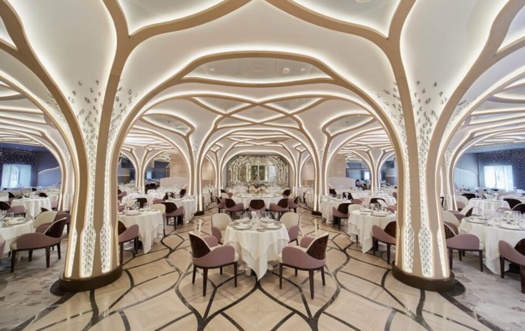 Eleganter, heller Speisesaal mit eingedeckten Tischen unter einer beleuchteten, geschwungenen Deckenkonstruktion in Form von weißen Baumkronen übergehend in Säulen als Baumstämmen. Eleganter, heller Speisesaal mit eingedeckten Tischen unter einer beleuchteten, geschwungenen Deckenkonstruktion in Form von weißen Baumkronen übergehend in Säulen als Baumstämmen.