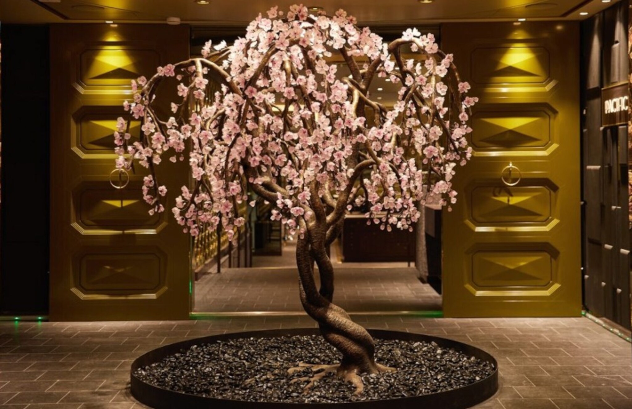 Skulptur in Baumform mit rosa Blüten in einem Rondell in einem eleganten Foyer.