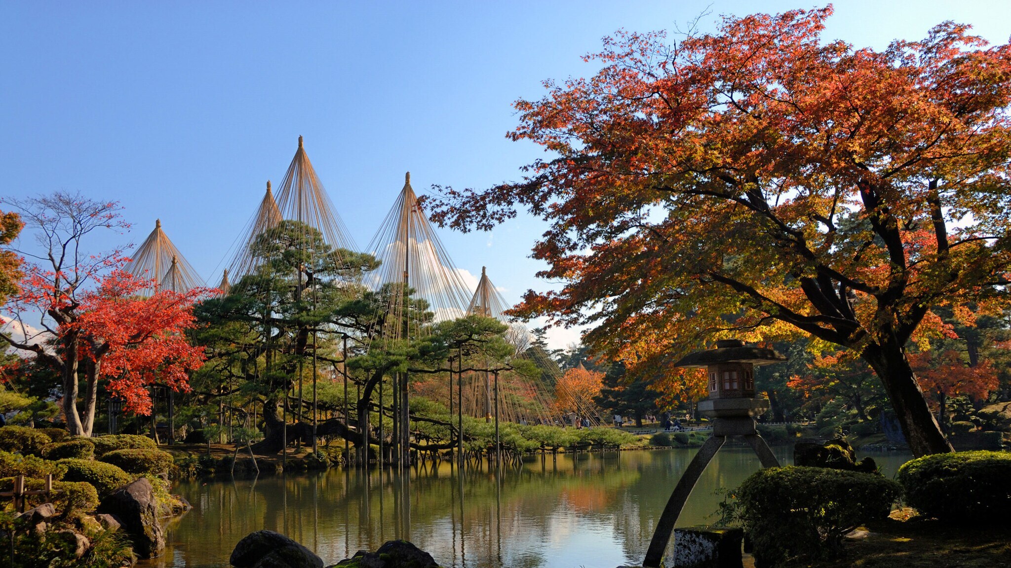 Herbstliche Landschaft im Kenrokuen-Garten mit Kotoji-Laterne am Teich und bunt gefärbten Bäumen