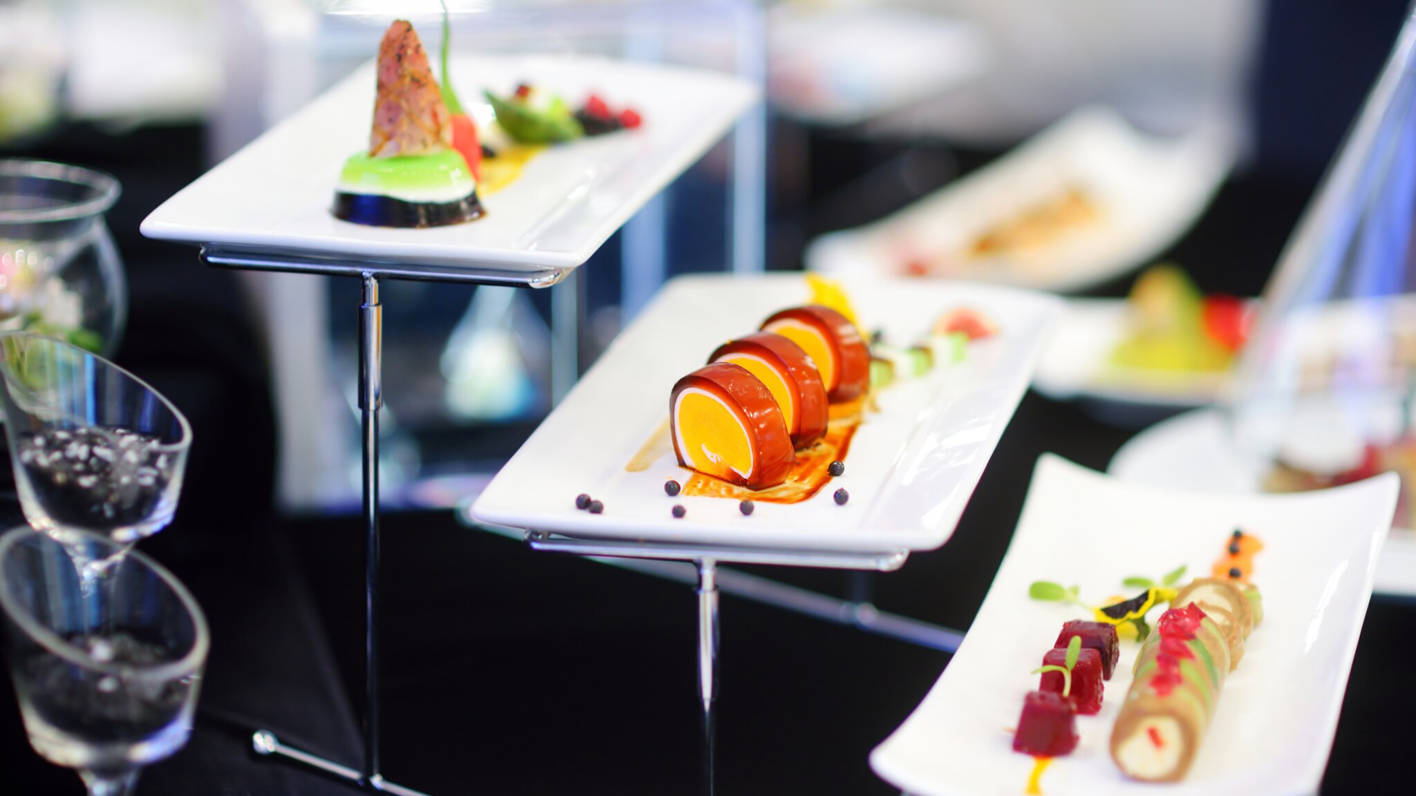 Verschiedene kunstvoll angerichtete Gourmet-Häppchen auf weißen rechteckigen Tellern bei einem Buffet