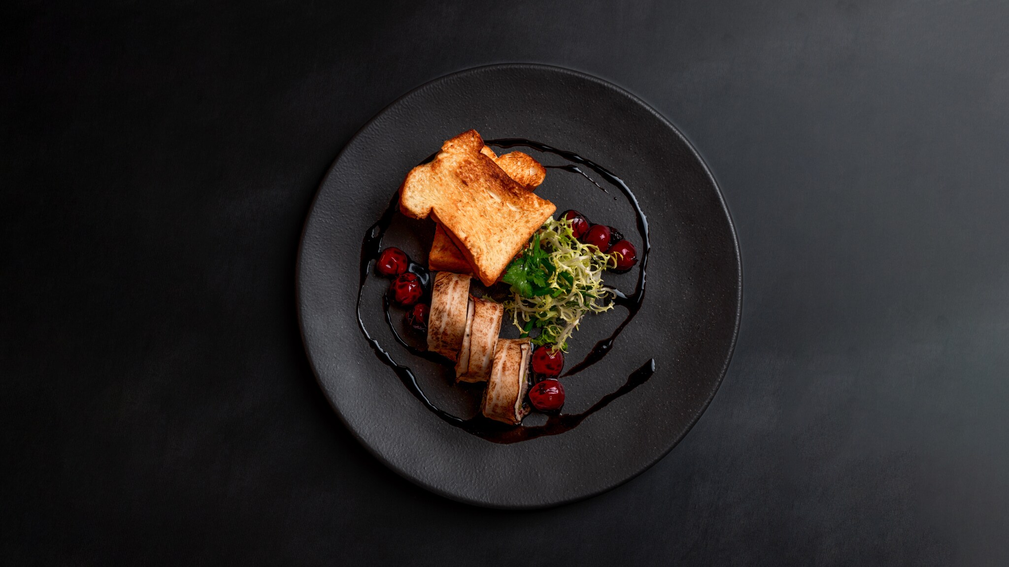 Schwarzer Teller mit zwei Scheiben geröstetem Brot, gegrilltem Fleisch, Salat und roten Beeren, angerichtet mit dunkler Sauce Schwarzer Teller mit zwei Scheiben geröstetem Brot, gegrilltem Fleisch, Salat und roten Beeren, angerichtet mit dunkler Sauce