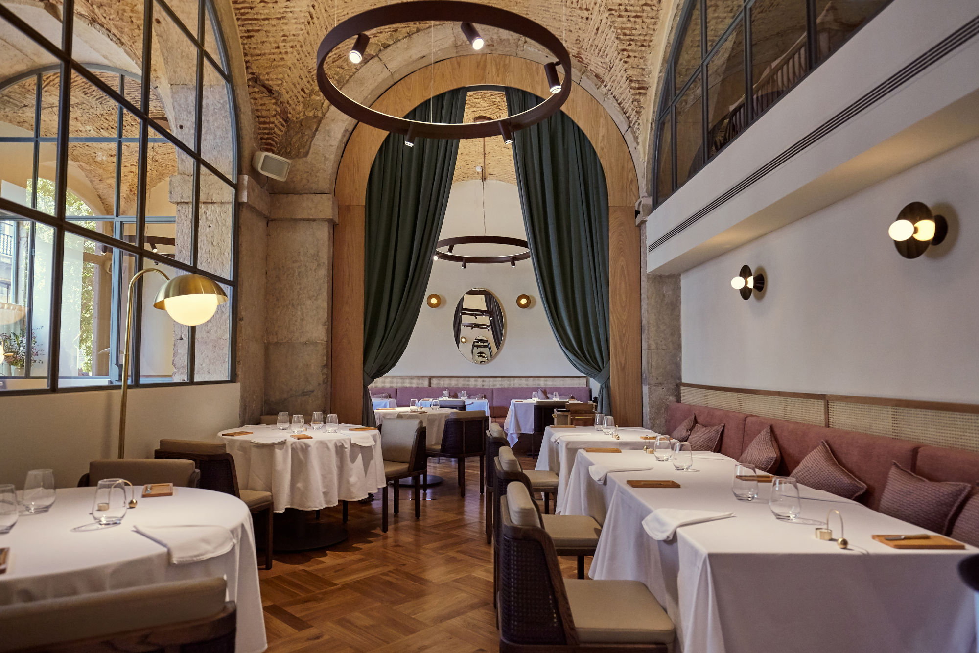 Interieur des Sternerestaurants Belcanto mit elegant eingedeckten Tischen, Designerlampen und historischem Gemäuer.