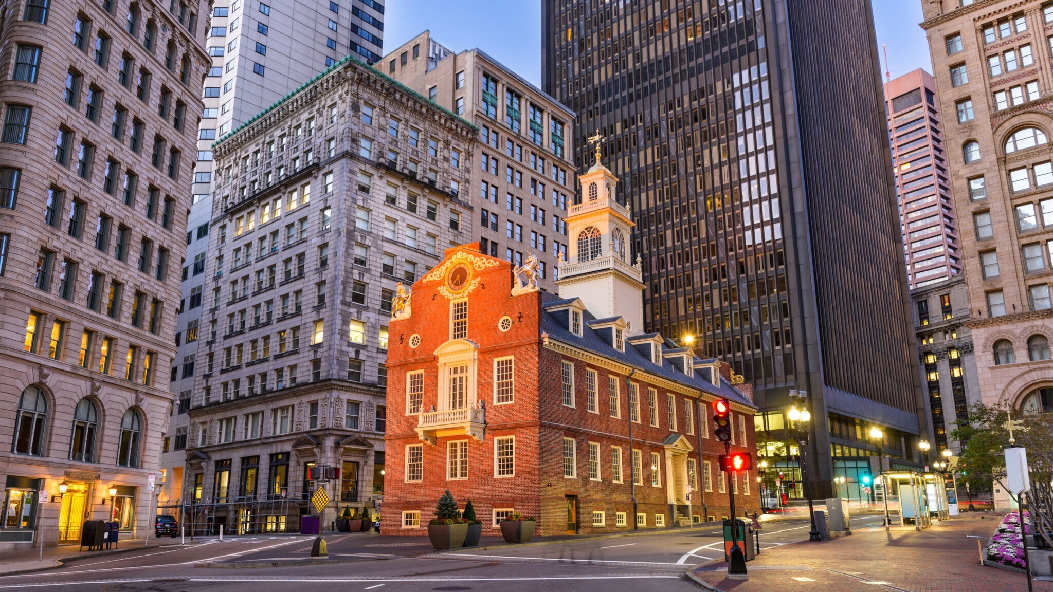Kreuzung in Boston vor dem Old State House bei Dämmerung mit hohen Gebäuden im Hintergrund.