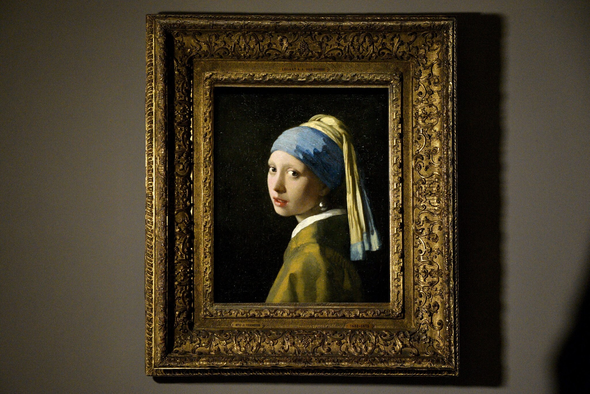 Das Ölgemälde Das Mädchen mit dem Perlenohrring in einem goldenen Rahmen an der Wand