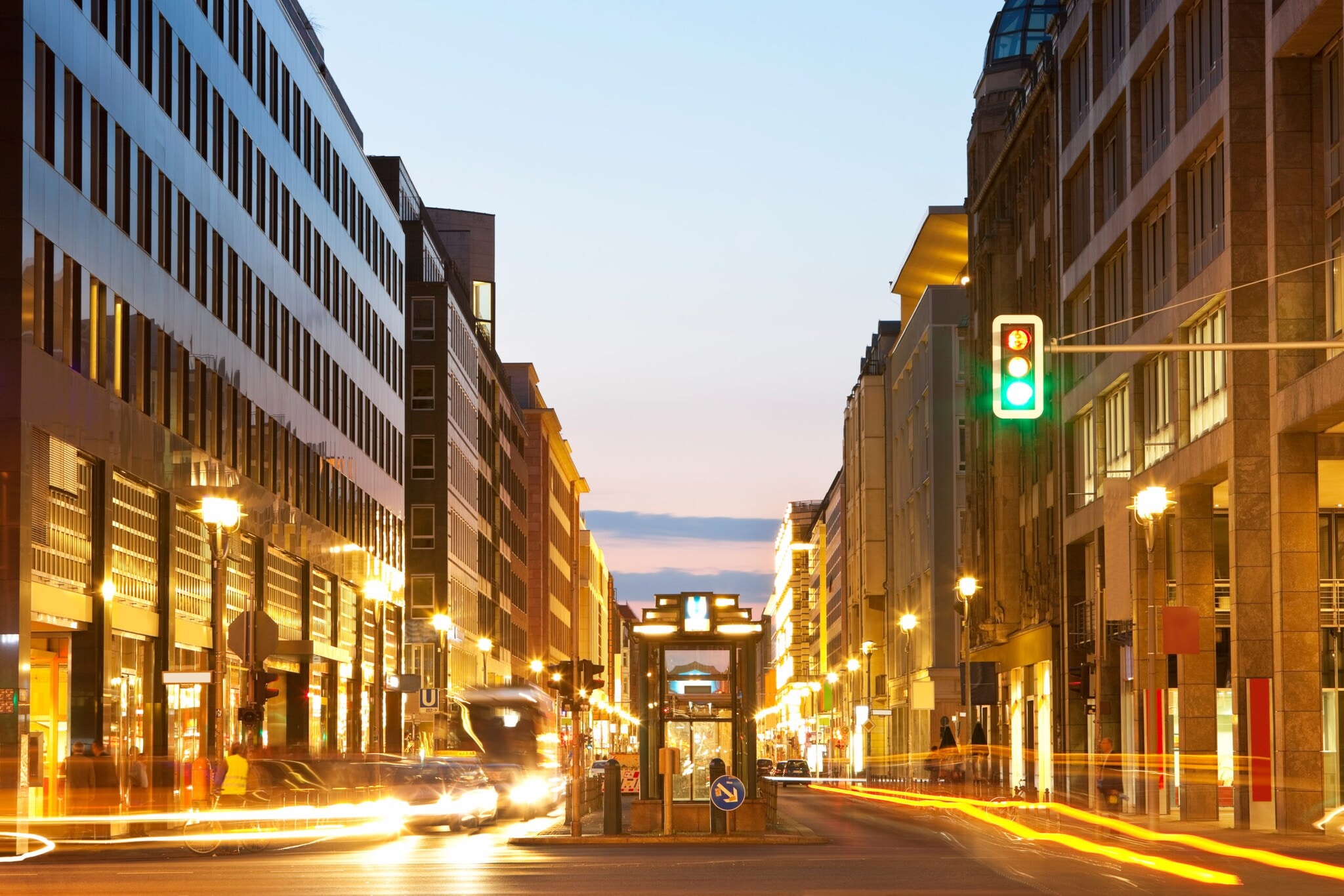 Zukunftsupdate 03/25: Sehen, was uns weiterbringt Fotografie mit langer Belichtungszeit einer befahrenen Straße während der Abenddämmerung, der Fokus liegt auf einer grünen Ampel.