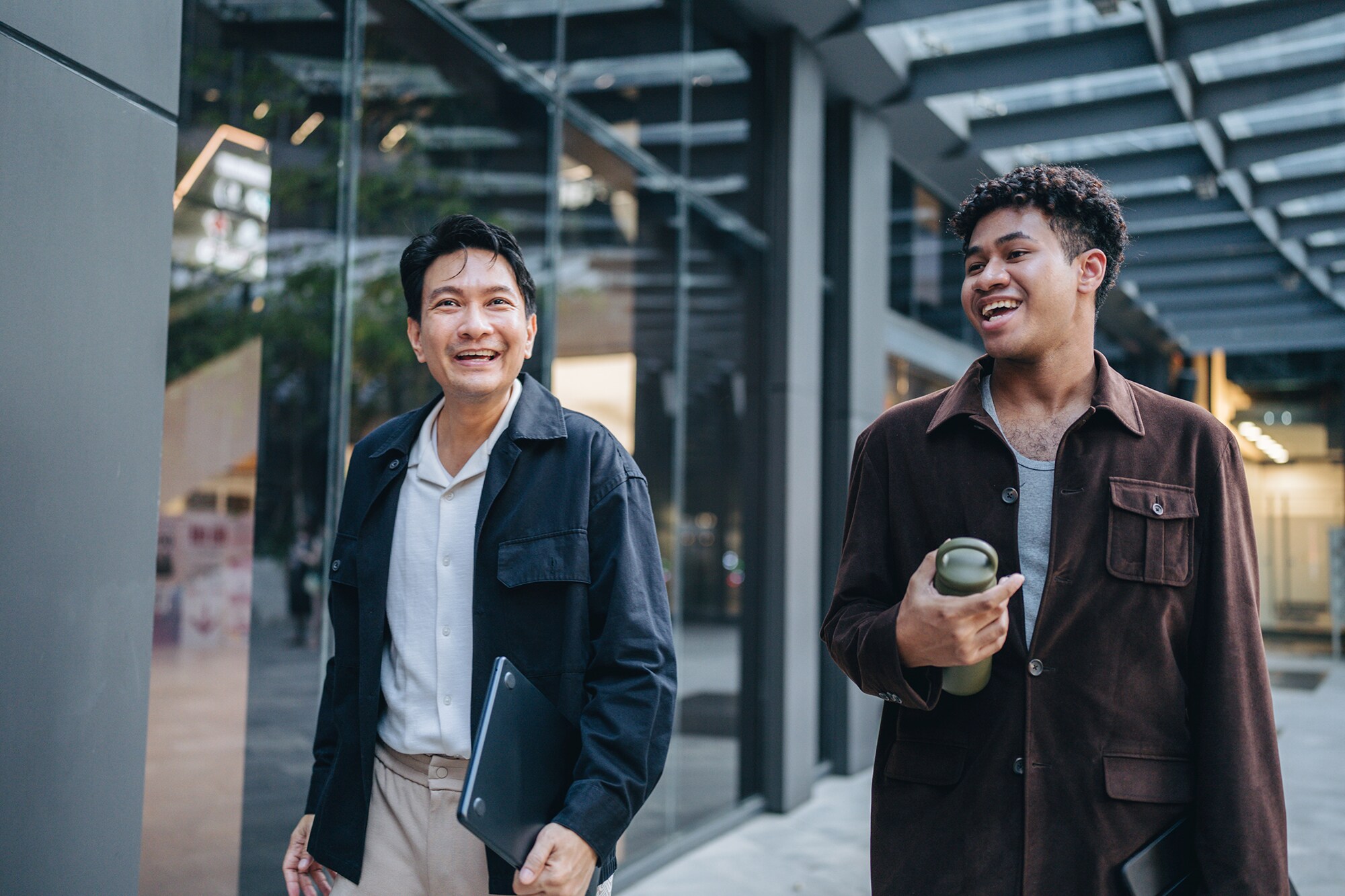 Zwei Kollegen spazieren gemeinsam und halten dabei eine Projektbesprechung ab.