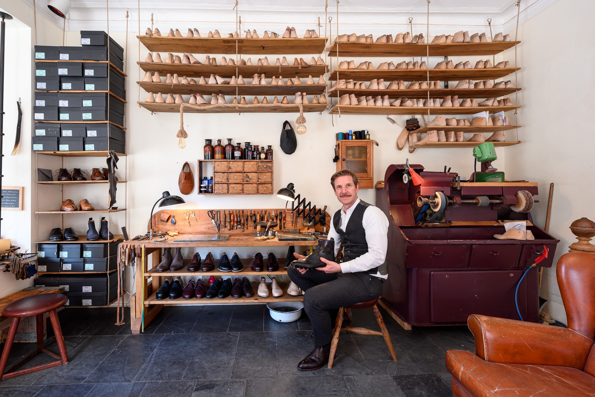 Schuster Thomas Keil sitzt auf einem Hocker in seiner Maßschuhmacherei.