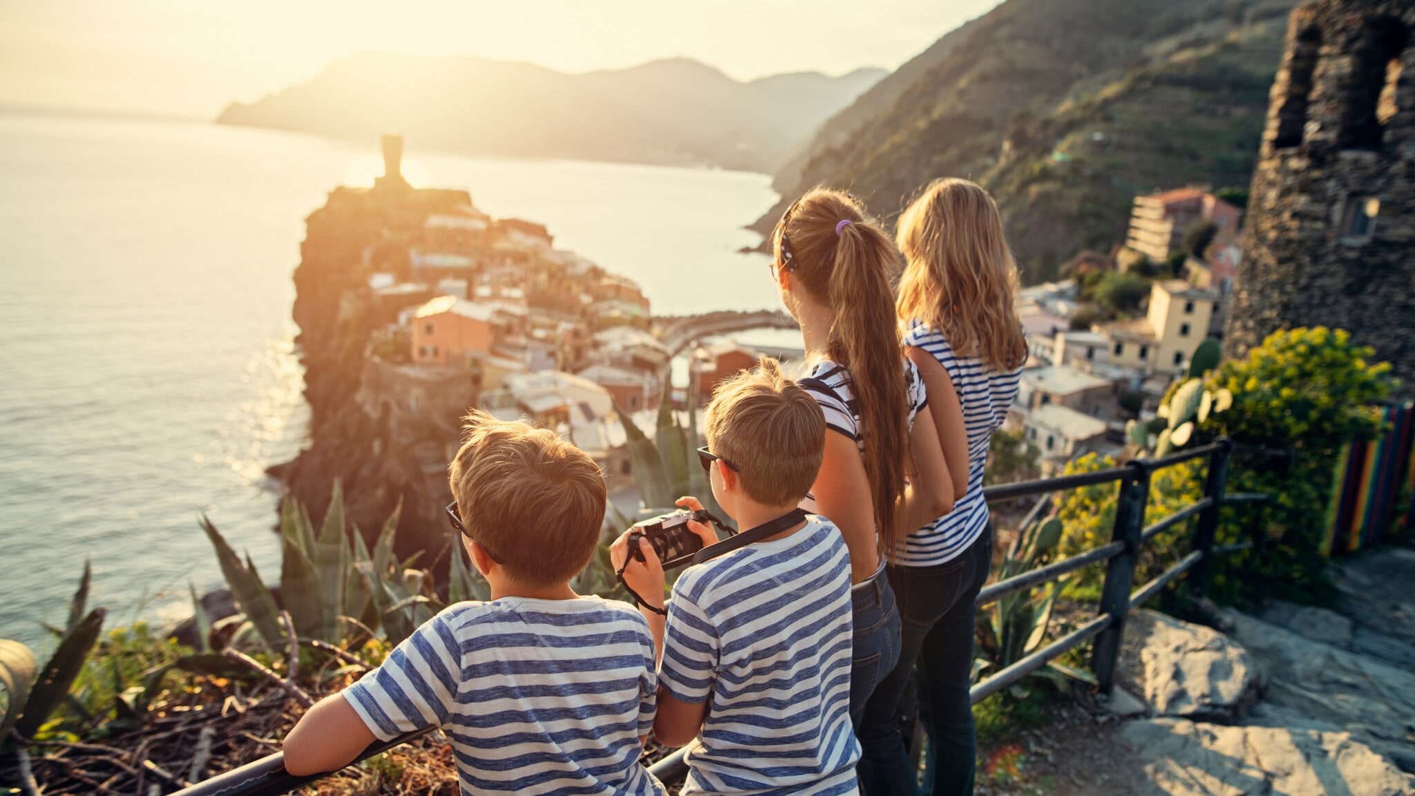 Familie blickt auf ein Küstendorf mit Meer und Bergen bei Sonnenuntergang Familie blickt auf ein Küstendorf mit Meer und Bergen bei Sonnenuntergang