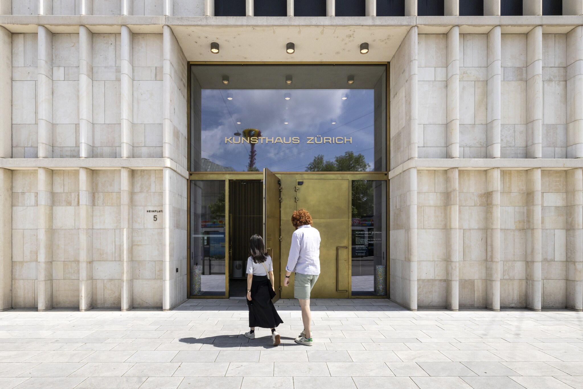 Rückansicht von zwei Personen vor dem Eingang des Kunsthauses Zürich in einem modernen Gebäude mit Marmorplatten.