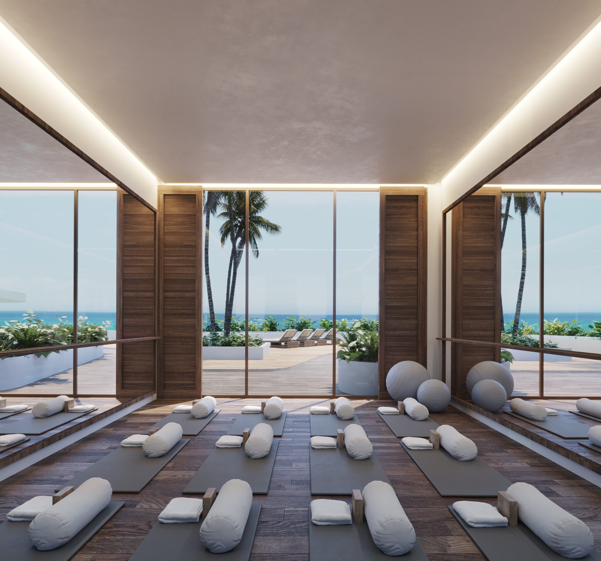Ein Yogaraum mit offenen Fenstern vor denen Wasser und Palmen liegen