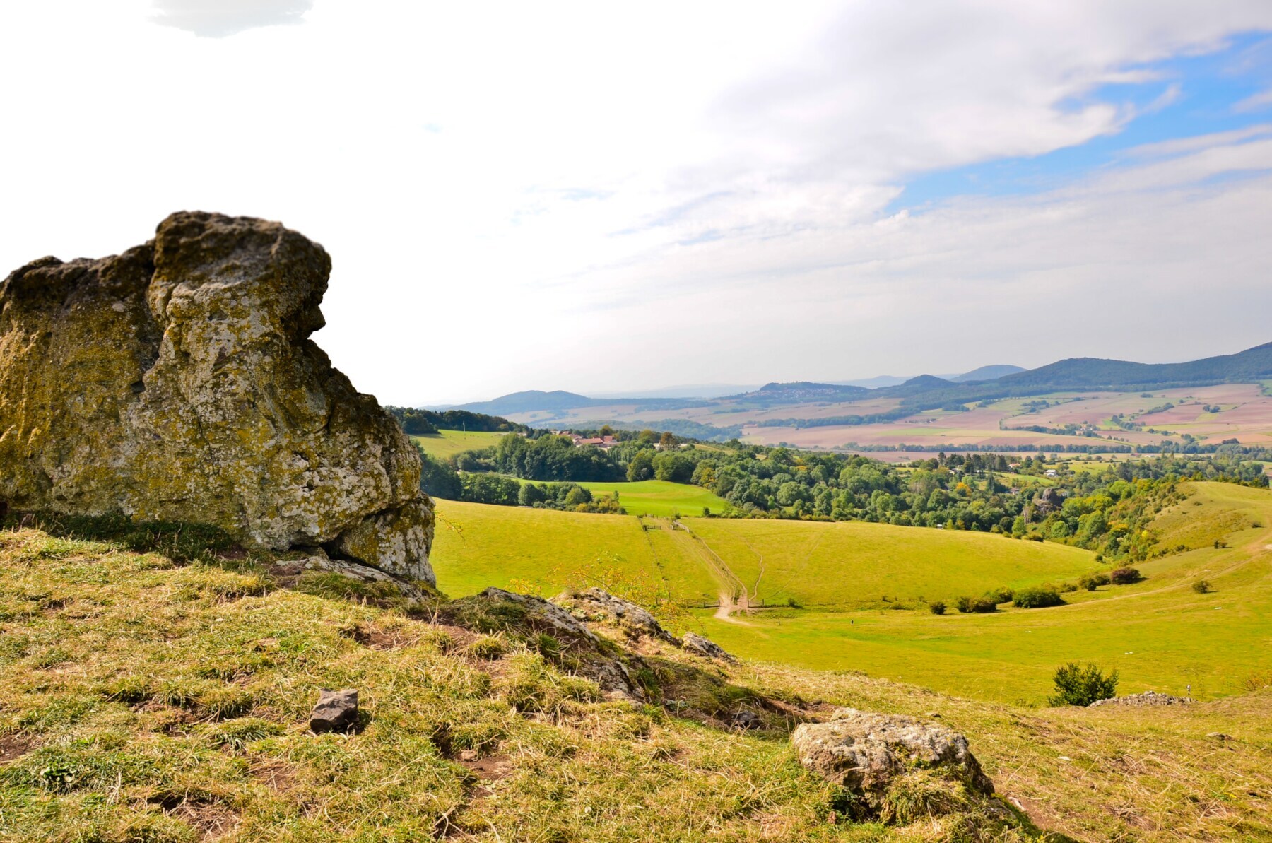 Blick auf Wiesen und Wälder, im Vordergrund eine Felsformation