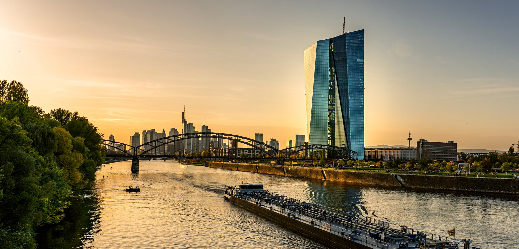 Feierabend Frankfurt Ein Schiff fährt auf dem Main, im Hintergrund sieht man den EZB-Turm und die Skyline von Frankfurt.
