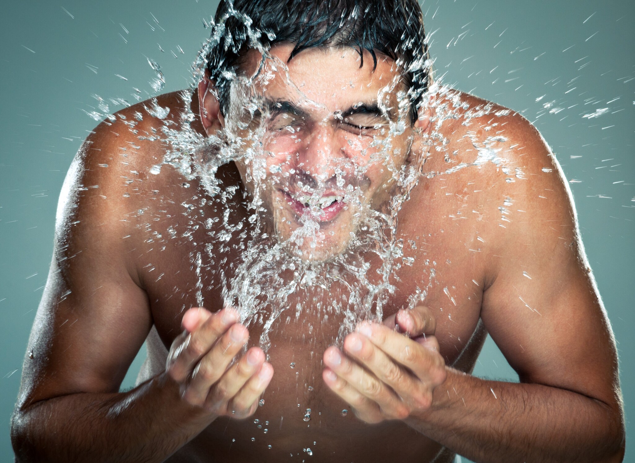 Ein Mann kühlt sein Gesicht mit kaltem Wasser.