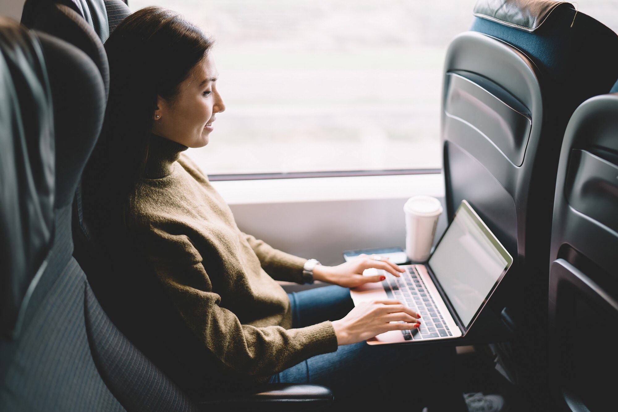 Geschäftsreise mit der Deutschen Bahn – 8 Fragen an Jan-Wolf Baake Eine Frau arbeitet in einem fahrenden Zug am Laptop.