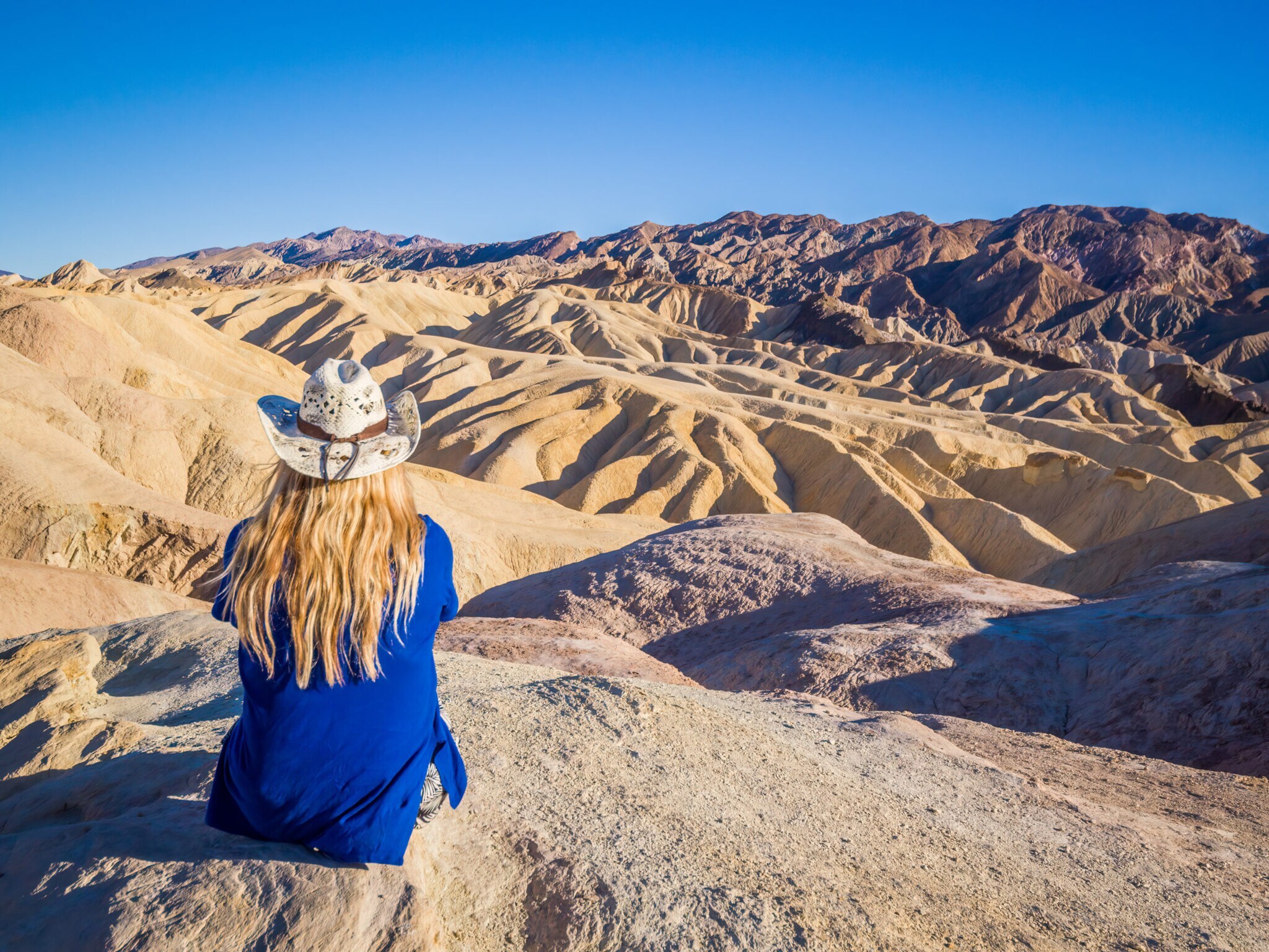 Eine Frau mit Sonnenhut schaut in die Wüstenlandschaft des Death Valley.