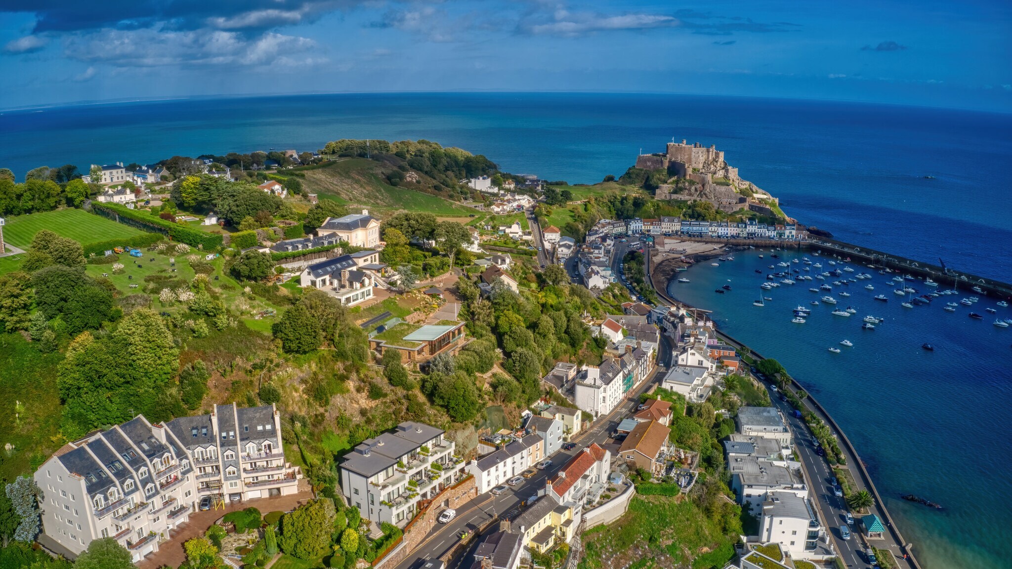 Landschaftspanorama eines Küstenortes mit grüner Vegetation und Rasenflächen in Hanglange mit Hafenareal. Landschaftspanorama eines Küstenortes mit grüner Vegetation und Rasenflächen in Hanglange mit Hafenareal.