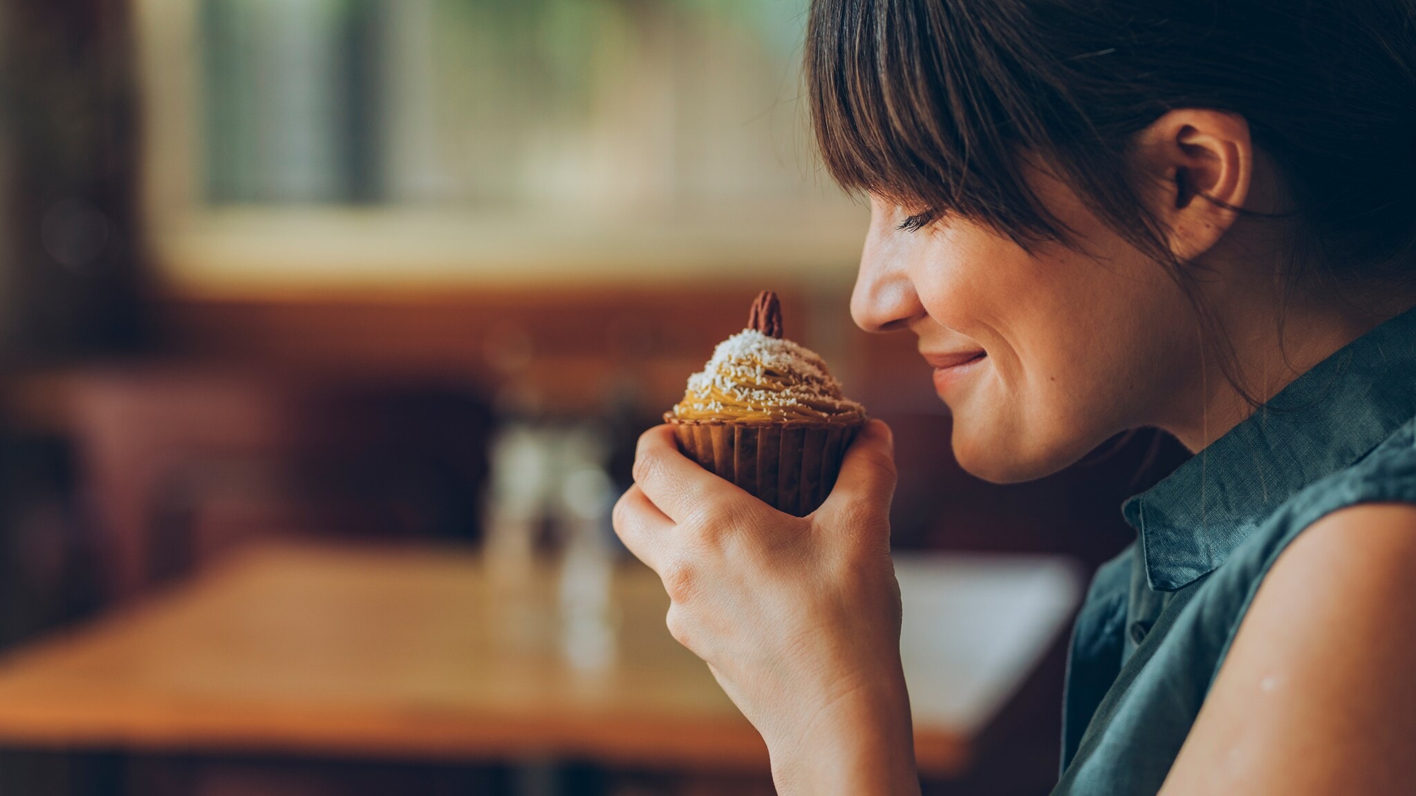 Eine Frau hält sich einen Nuss-Muffin an die Nase und lächelt, ihre Augen sind geschlossen. Eine Frau hält sich einen Nuss-Muffin an die Nase und lächelt, ihre Augen sind geschlossen.