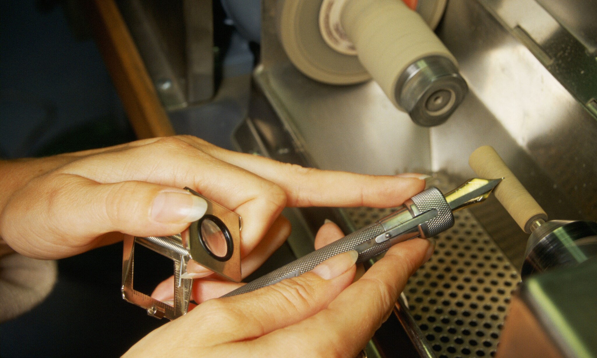 Eine feminine Hand hält eine goldene Feder eines Füllers und schleif diese