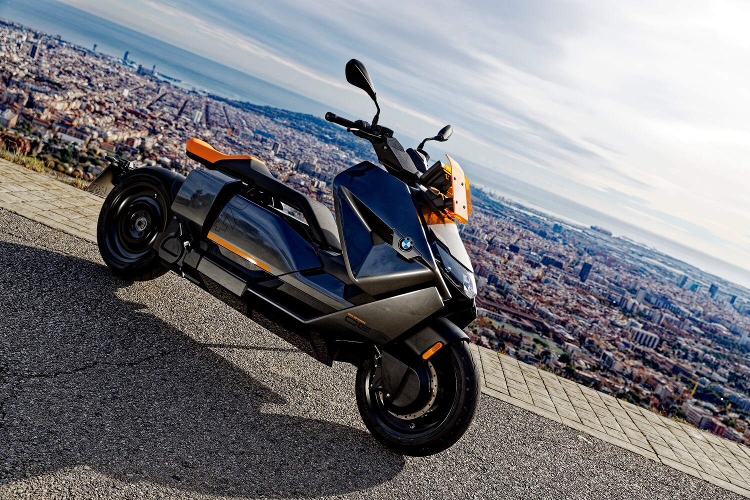 Der Elektro-Großroller BMW CE 04 parkt auf einem Plateau mit Blick auf Barcelona.