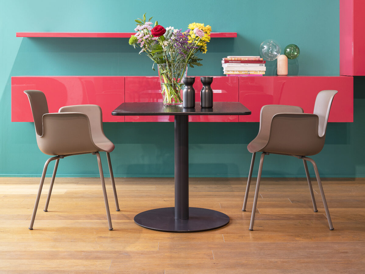 Zwei braune Plastikstühle stehen um einen schwarzen Bistrotisch Zwei braune Plastikstühle stehen um einen schwarzen Bistrotisch