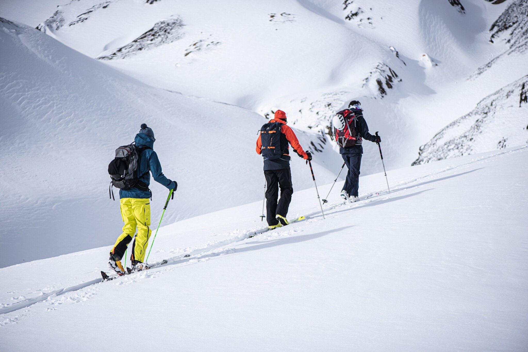 Drei Schneeschuhwander:innen auf einem verschneiten Berg