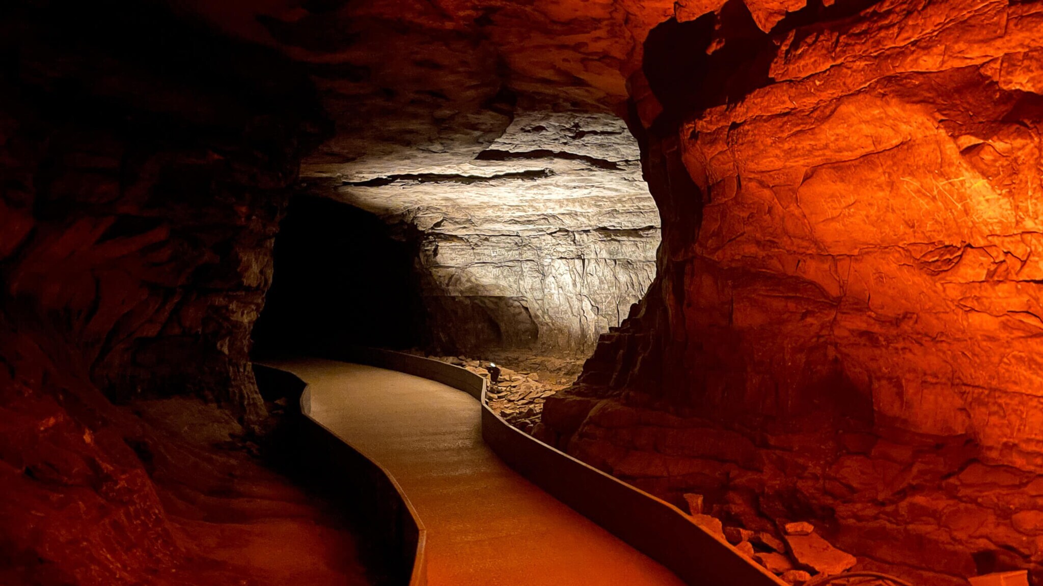 Beleuchteter Weg durch eine Höhle mit roten und weißen Felswänden im Mammoth Cave Nationalpark