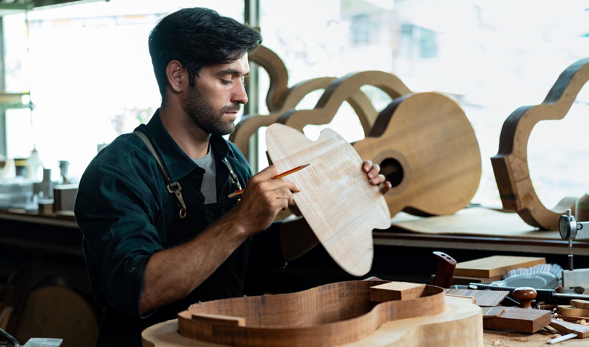 12_hobby-zum-beruf-machen_inline_image_1 Ein Mann fügt den Korpus einer Gitarre zusammen.