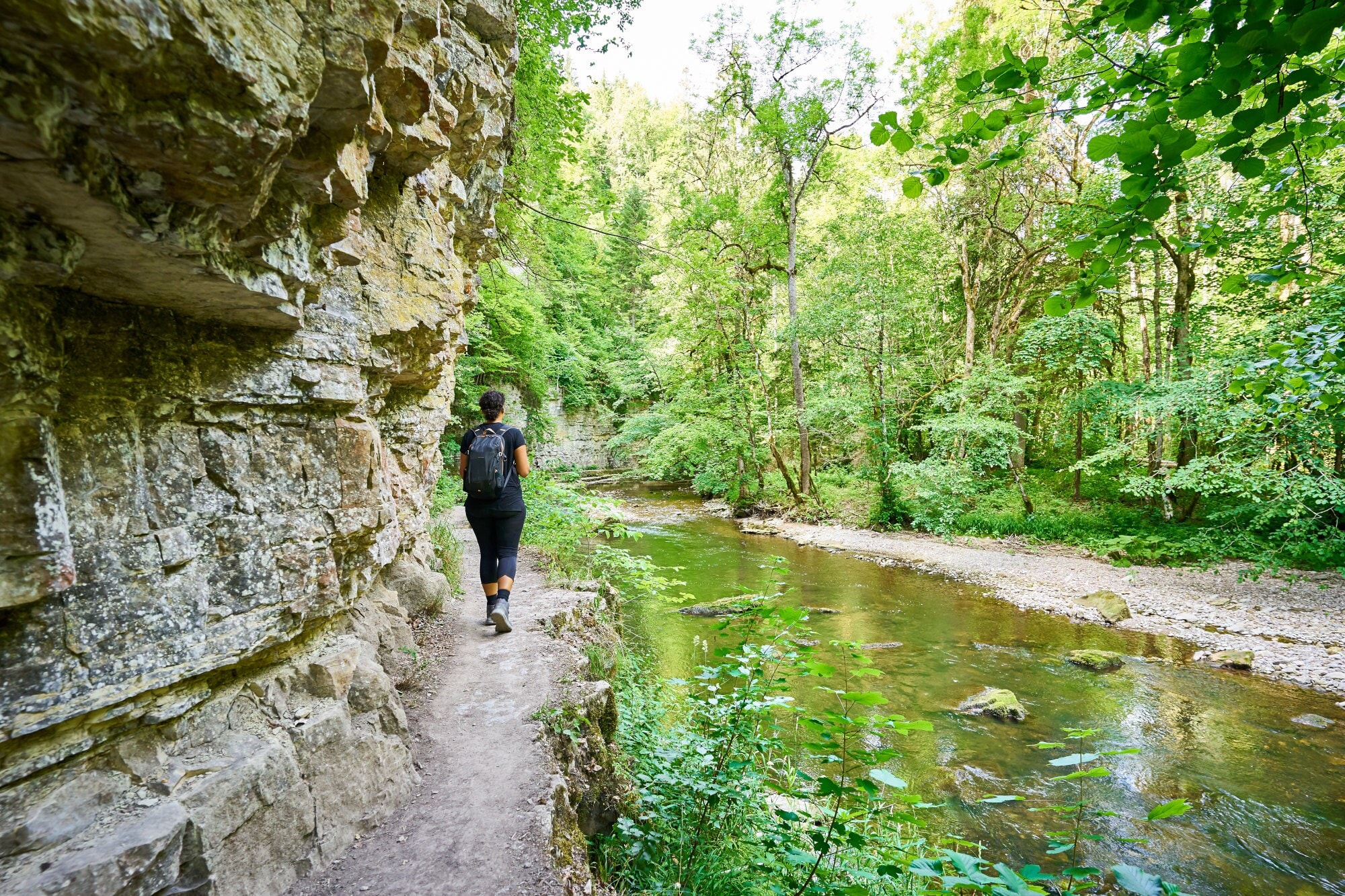 Eine Person wandert in der Wutachschlucht, entlang schroffer Felswänden und einem idyllischen Bachlauf. Eine Person wandert in der Wutachschlucht, entlang schroffer Felswänden und einem idyllischen Bachlauf.