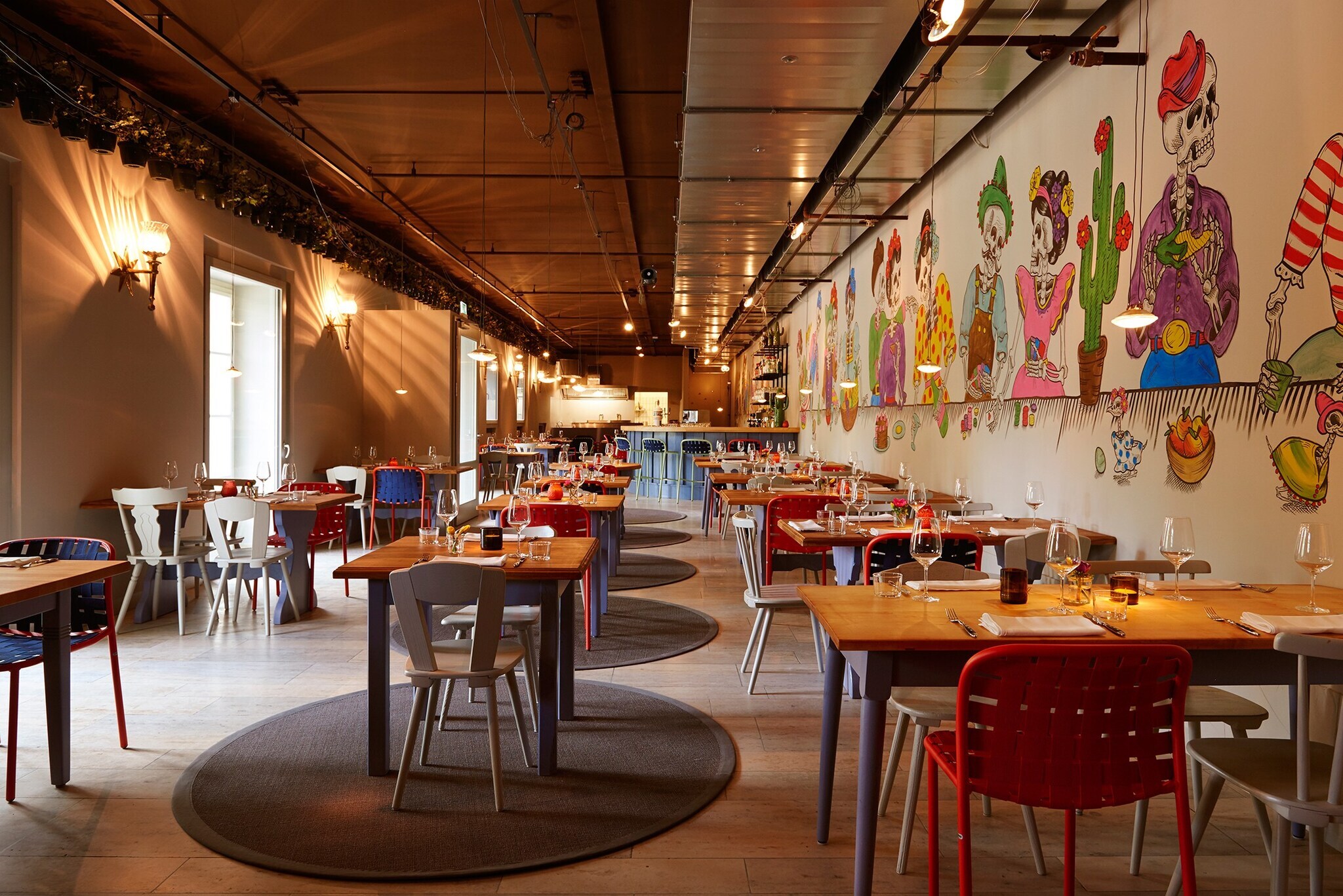 Innenaufnahme eines Restaurants mit Holztischen und bemalten Wänden