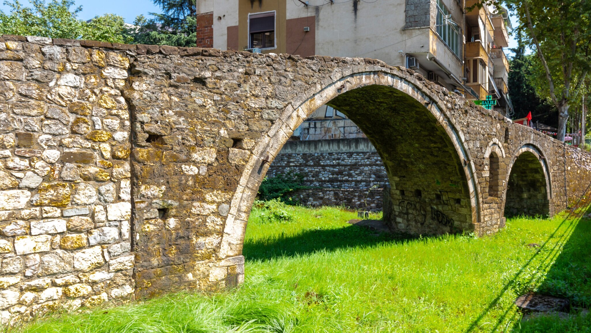 Steinbogenbrücke über einem ehemaligen Flusslauf Grasfläche in einem Stadtgebiet. Steinbogenbrücke über einem ehemaligen Flusslauf Grasfläche in einem Stadtgebiet.