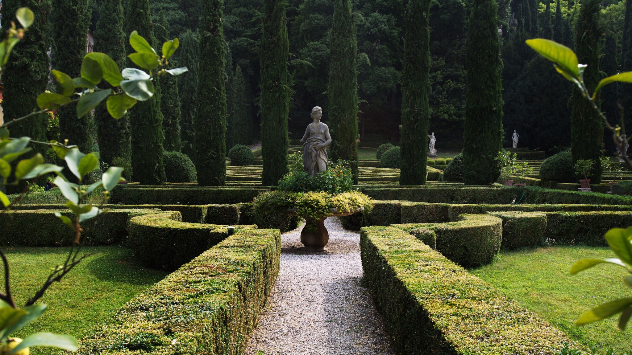 Renaissancegarten mit Zypressen und Steinstatuen in einem Heckenlabyrinth.