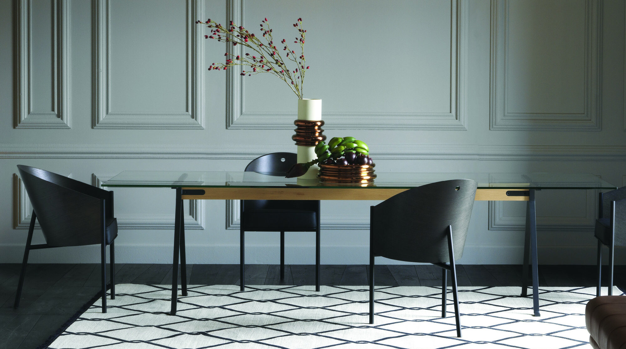 Drei graue Stühle stehen um einen Tisch mit Blumendekoration Drei graue Stühle stehen um einen Tisch mit Blumendekoration