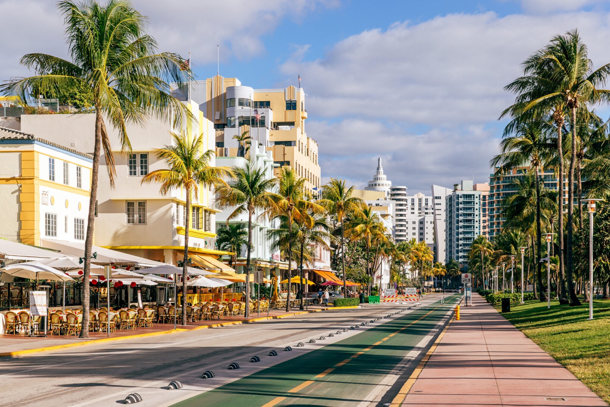 Palmengesäumte Promenade mit Art-déco-Gebäuden und Straßencafés.