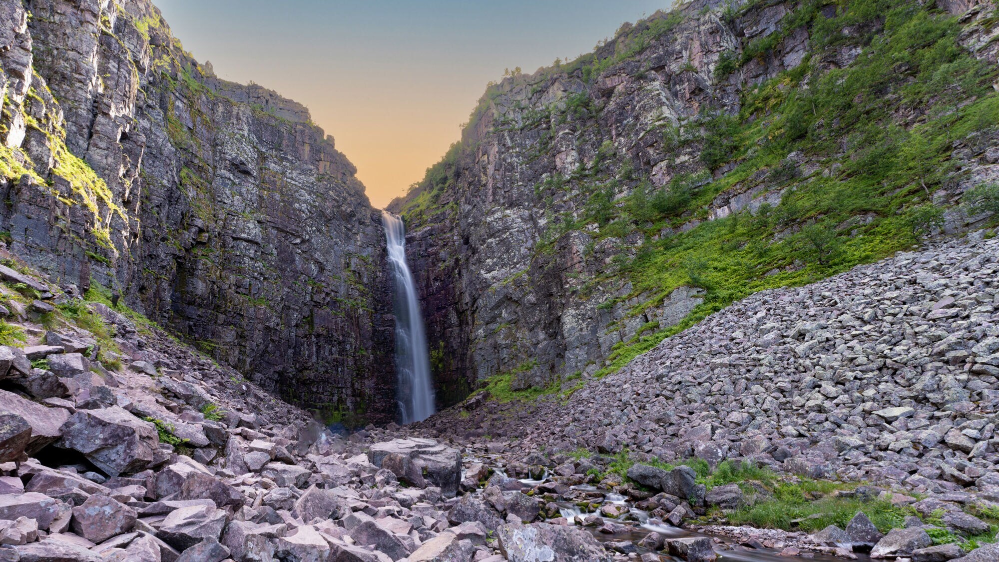 Hoher Wasserfall, der in einer Schlucht über eine steile Felswand in ein Felsbett stürzt. Hoher Wasserfall, der in einer Schlucht über eine steile Felswand in ein Felsbett stürzt.