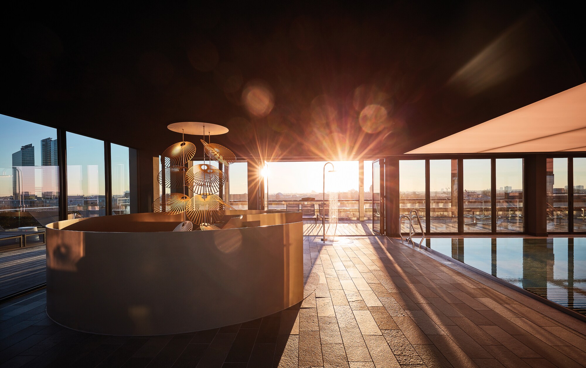 Die Sonne scheint durch eine Glasfront in einen Spabereich mit Wanne und Pool Die Sonne scheint durch eine Glasfront in einen Spabereich mit Wanne und Pool