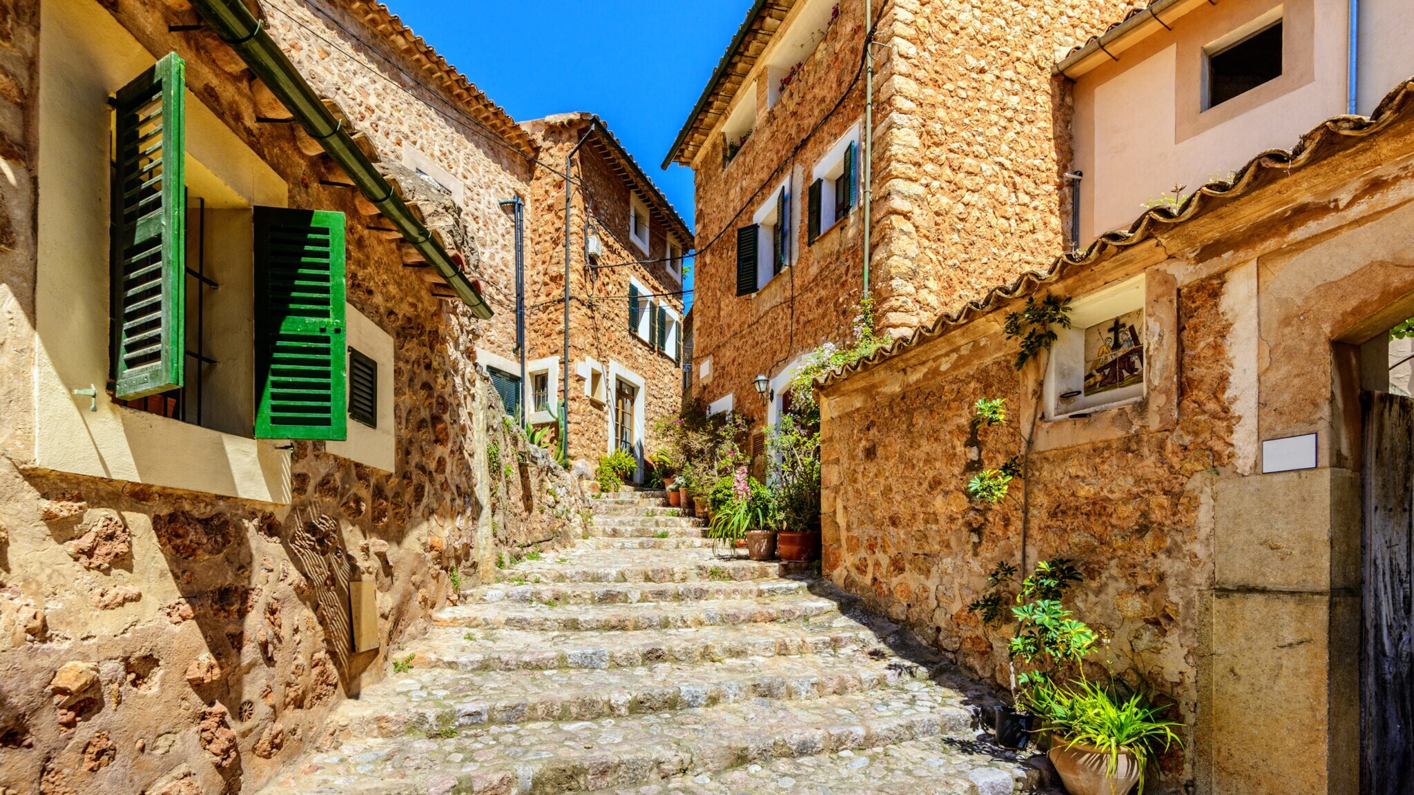 Steinweg mit Stufen zwischen traditionellen Häusern aus Naturstein mit grünen