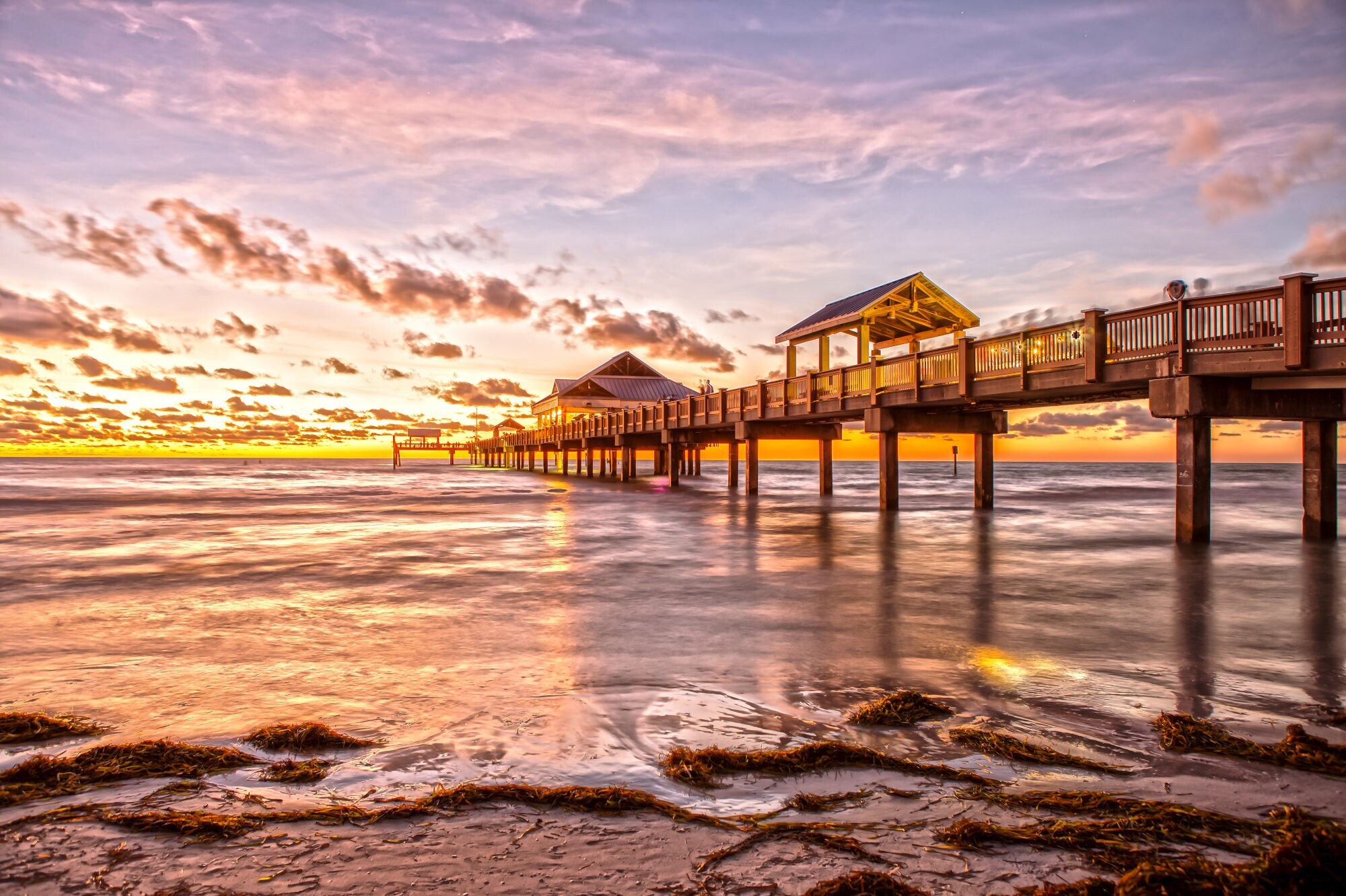 Der berühmte Pier 60 bei Sonnenuntergang mit goldgelbem Lichtspiel am Horizont.
