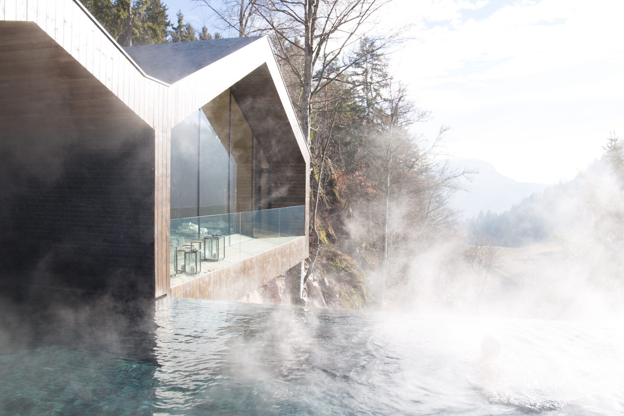 In einem Pool ohne Geländer mit Blick über die Berge schwimmt ein Mensch In einem Pool ohne Geländer mit Blick über die Berge schwimmt ein Mensch