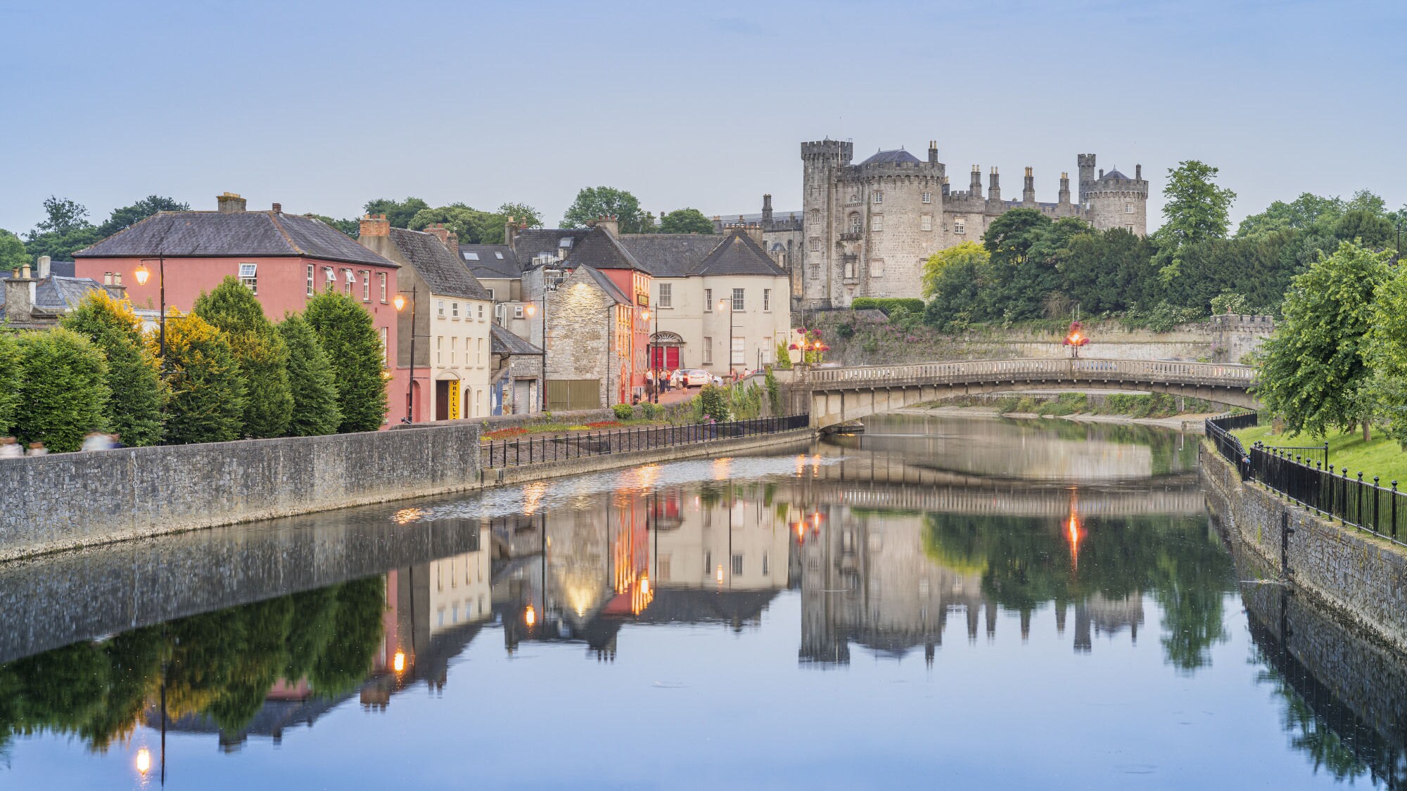 Blick auf Kilkenny mit Kilkenny Castle und der John’s Bridge vor dem Fluss Nore, indem sich die Lichter und Gebäude siegeln.