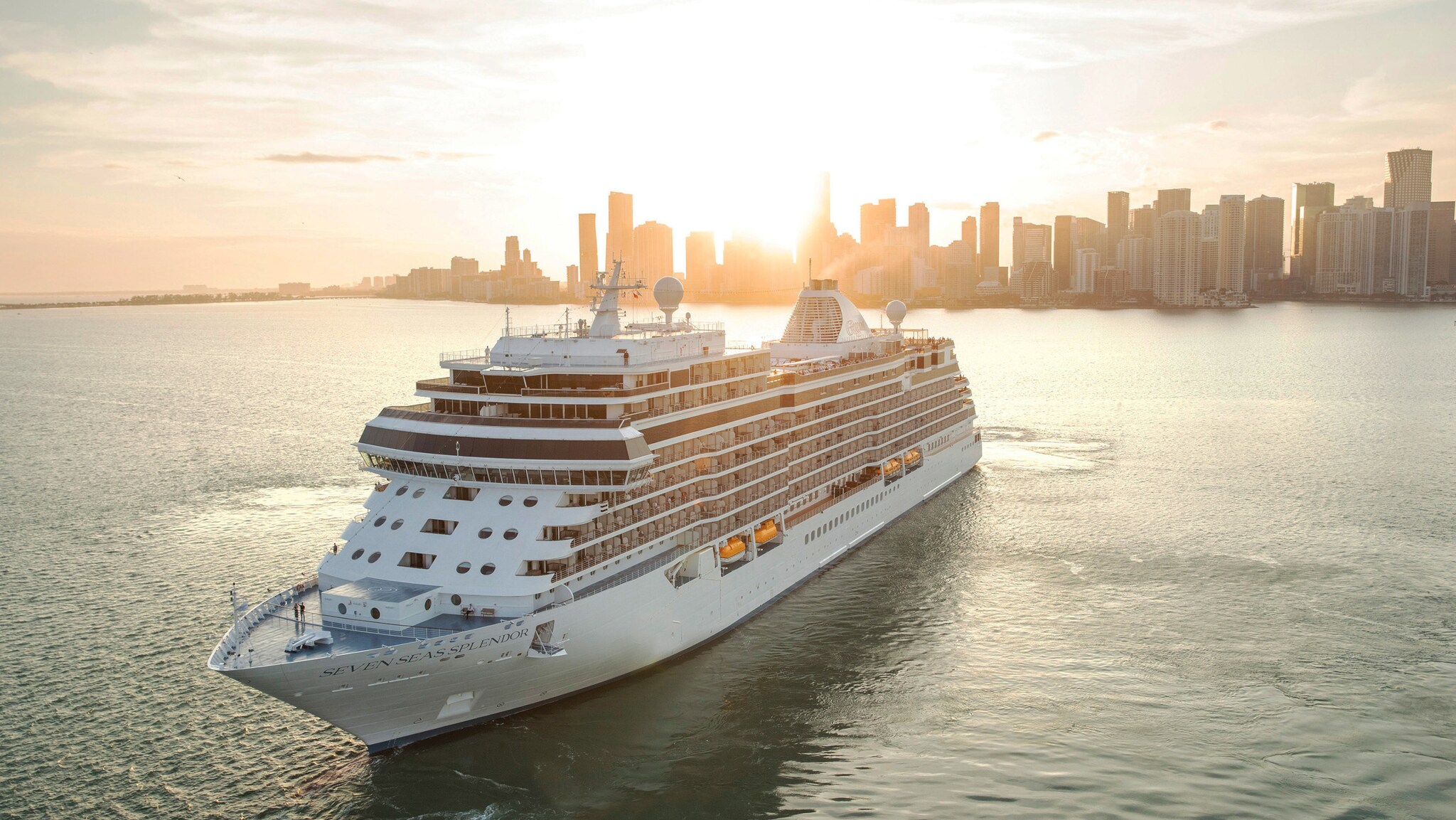 Kreuzfahrtschiff Seven Seas Splendor fährt vor der Skyline von Miami bei Sonnenuntergang.