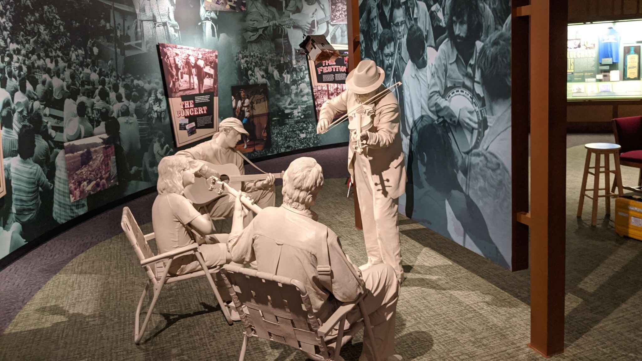 Drei weiße Skulpturen spielen Bluegrass-Musikinstrumente in einem Museum mit historischen Fotos an den Wänden Drei weiße Skulpturen spielen Bluegrass-Musikinstrumente in einem Museum mit historischen Fotos an den Wänden