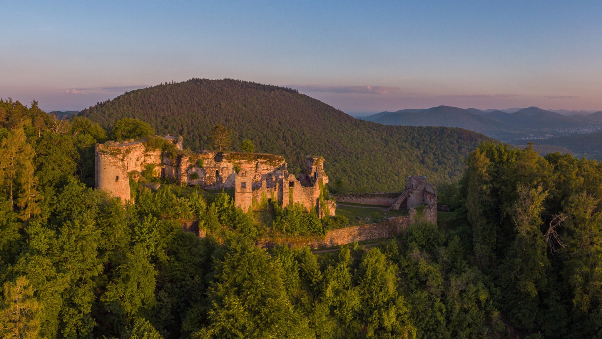 Panoramablick auf den Pfälzerwald mit Burgruine im Sonnenaufgang