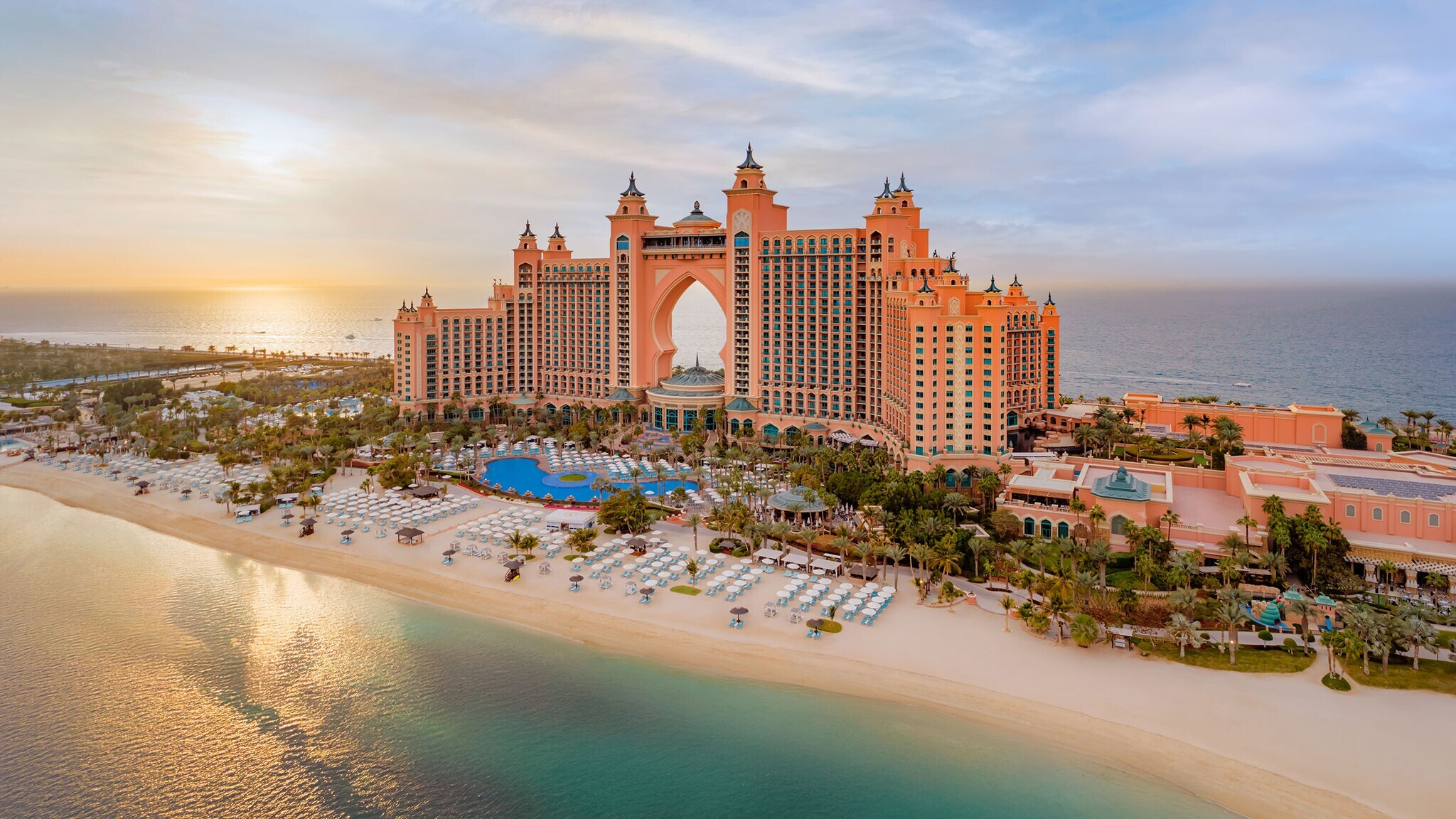 Luxuriöser Hotelkomplex mit Türmen auf einer Insel mit Gartenanlage und Pool an weißem Sandstrand.