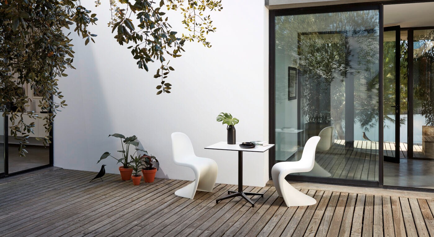 Zwei weiße Plastikstühle stehen um einen Bistrotisch herum