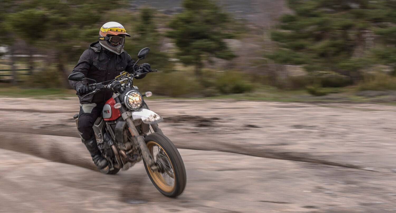 Ein Motorradfahrer driftet auf einer roten Ducati über eine Sandpiste.